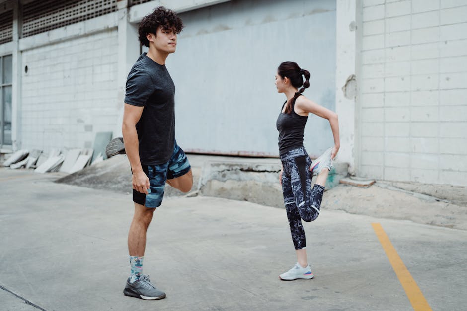 Two people stretching outdoors, focusing on balance and fitness in an urban setting.