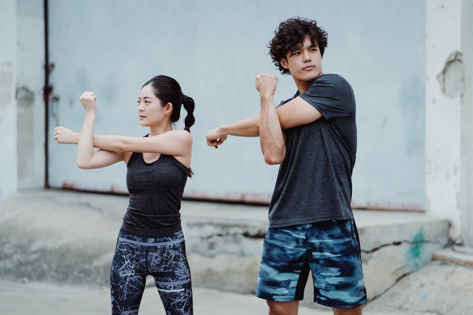 Young couple in activewear stretching outdoors, focused on fitness and health.